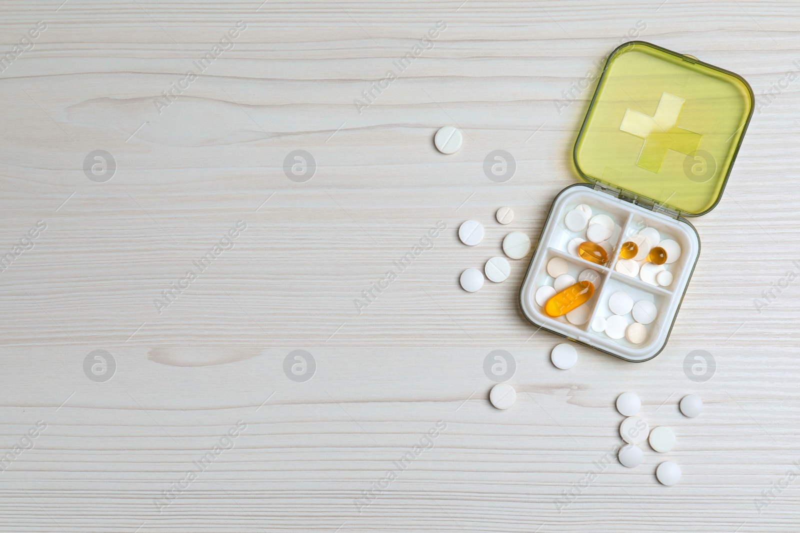 Photo of Pill box with medicaments on white wooden table, flat lay. Space for text