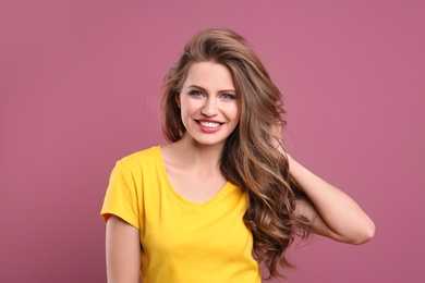 Portrait of young woman with long beautiful hair on color background