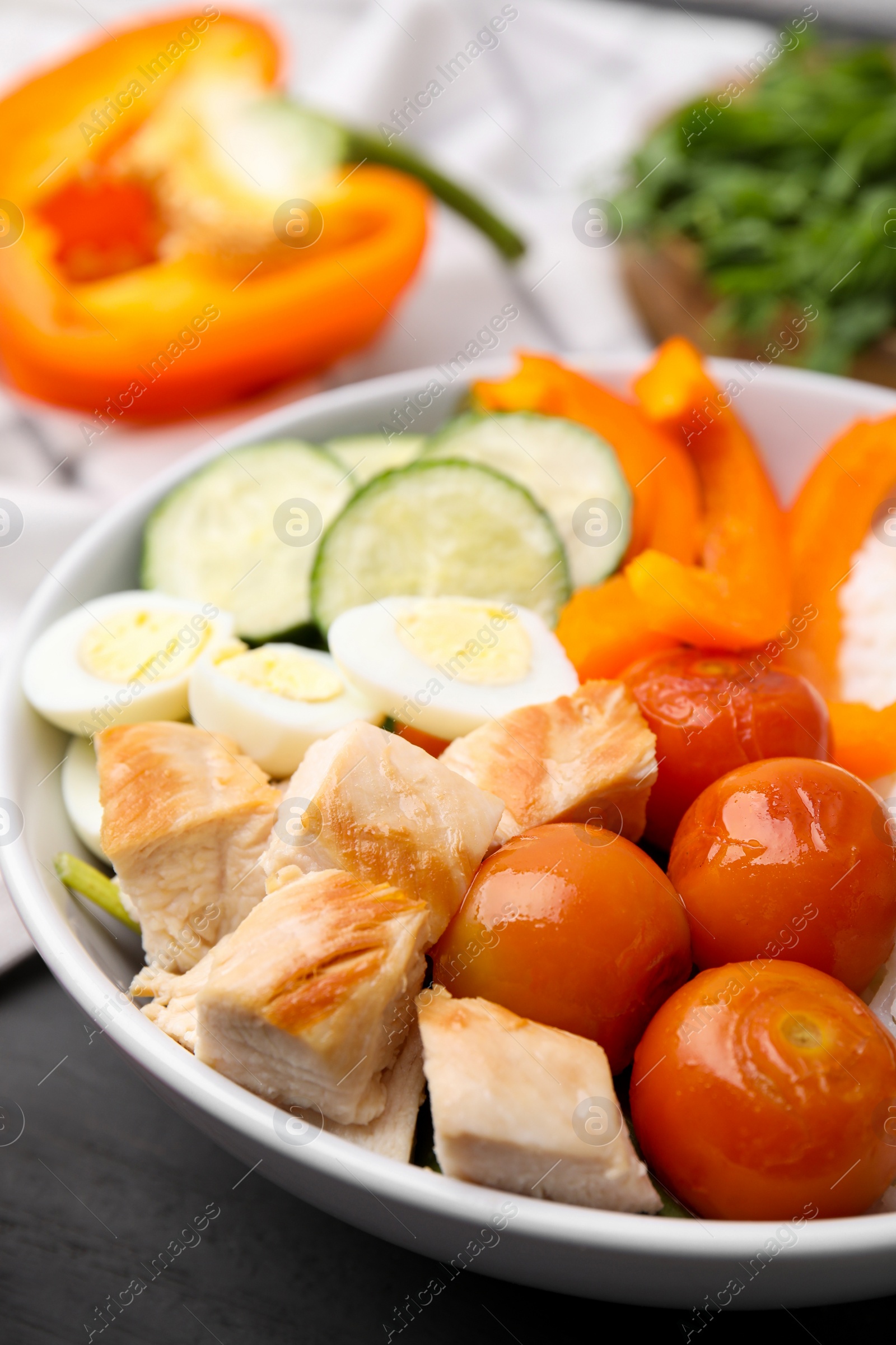 Photo of Delicious poke bowl with meat, rice, eggs and vegetables on black wooden table, closeup