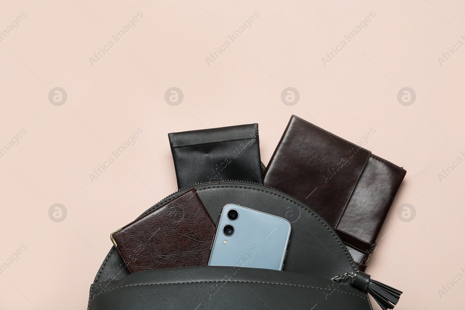 Photo of Stylish backpack with accessories and smartphone on beige background, top view