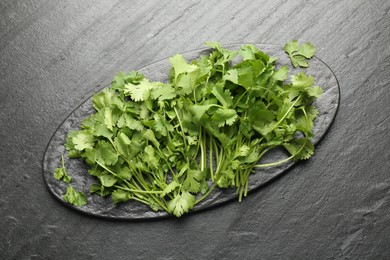 Photo of Fresh coriander on dark gray textured table, top view