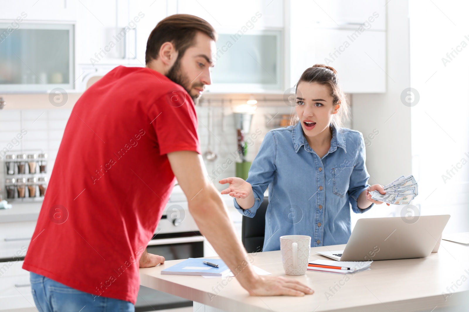 Photo of Young couple having argument about family budget in kitchen