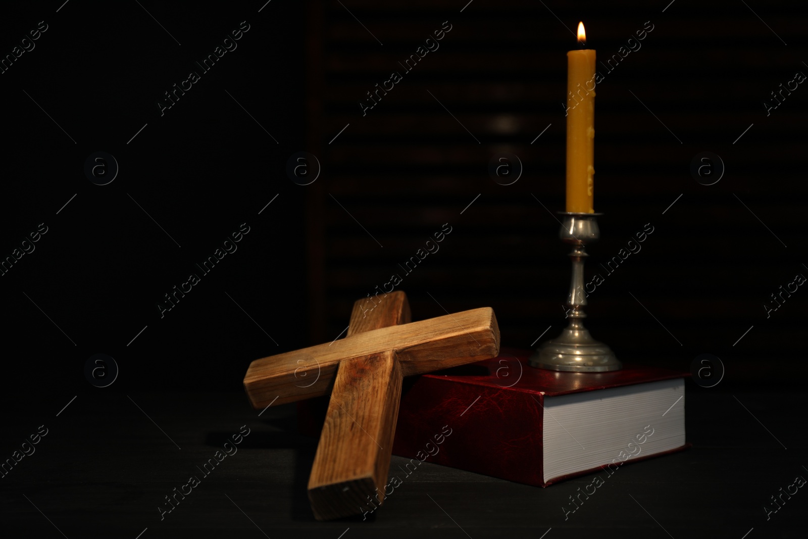 Photo of Church candle, Bible and wooden cross on table, space for text
