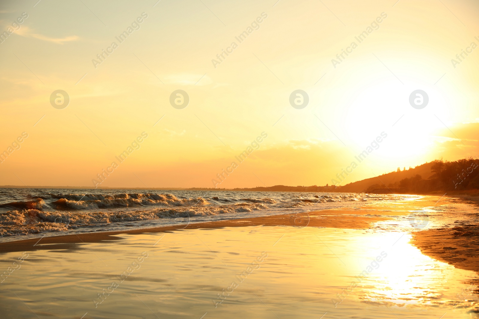 Photo of Picturesque view of sandy beach near sea at sunset