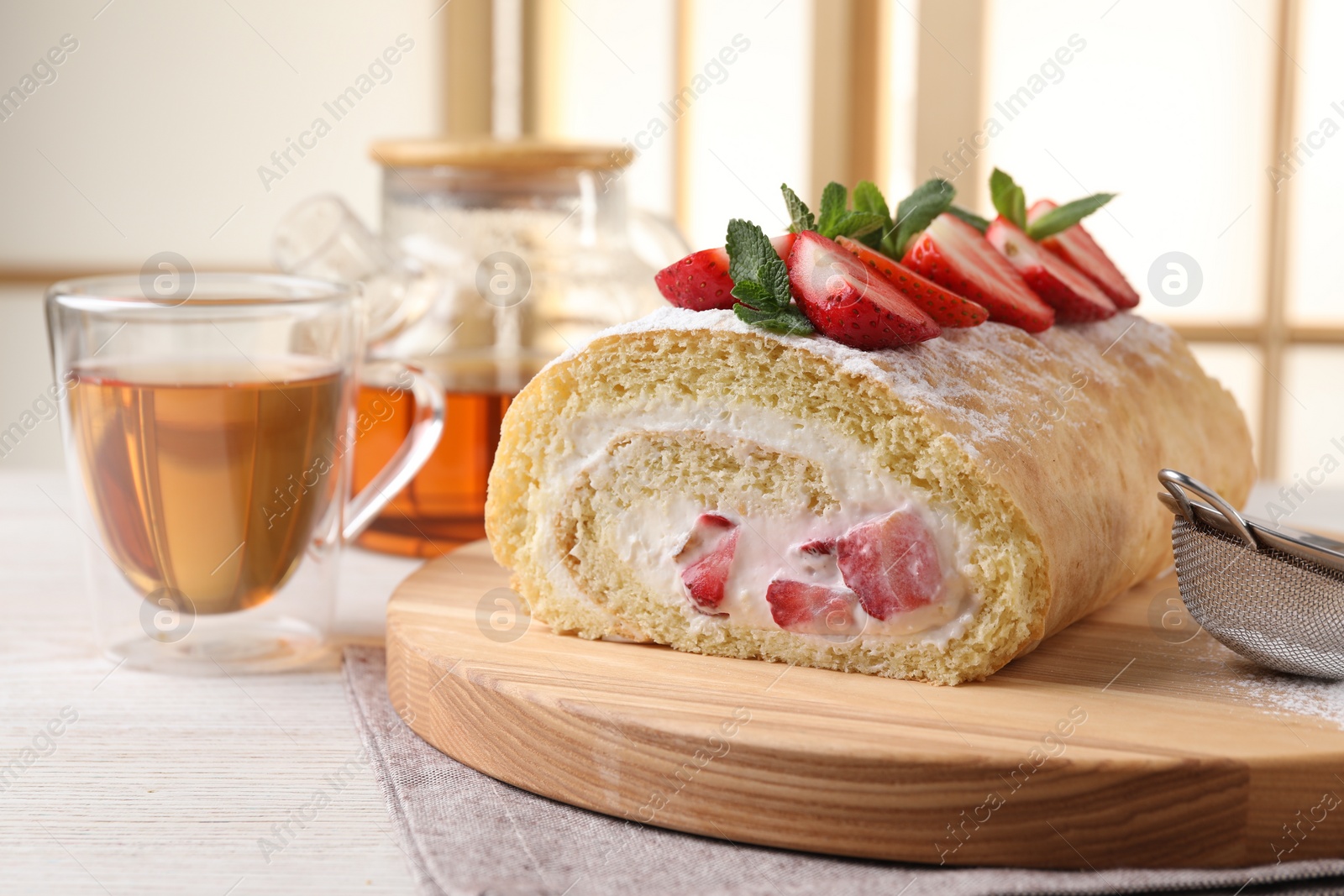 Photo of Delicious cake roll with strawberries and cream on table indoors