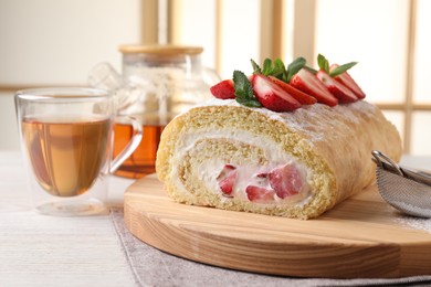 Photo of Delicious cake roll with strawberries and cream on table indoors