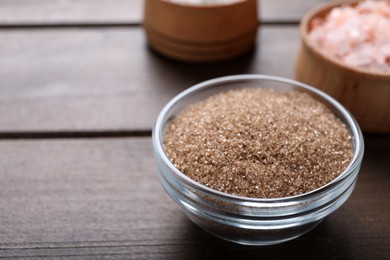 Photo of Salt in glass bowl on wooden table, space for text