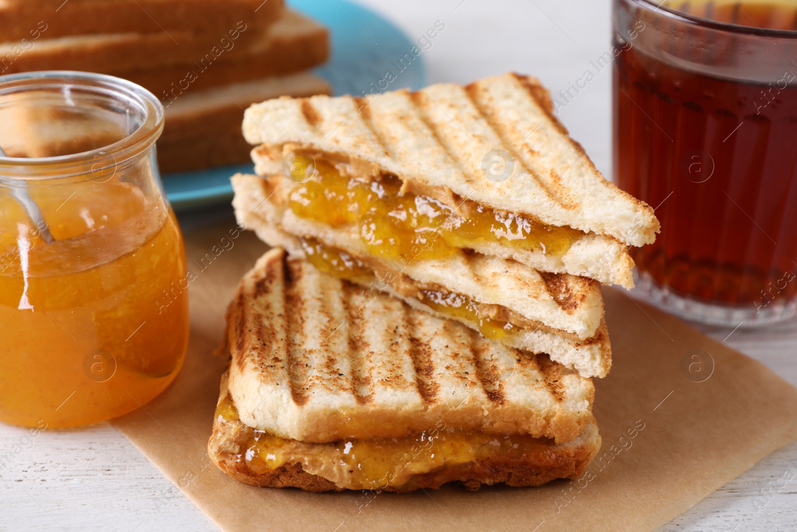 Image of Tasty sandwiches with apricot jam and peanut butter for breakfast on table, closeup