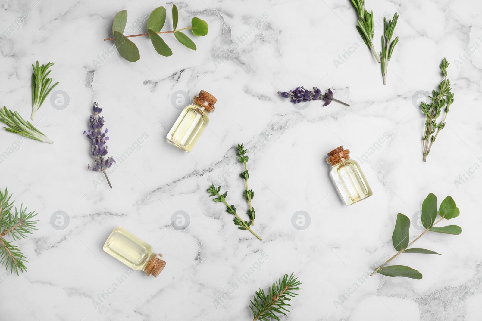 Photo of Different essential oils in glass bottles and ingredients on marble background, flat lay