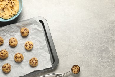 Bowl with dough and uncooked chocolate chip cookies on light grey table, flat lay. Space for text
