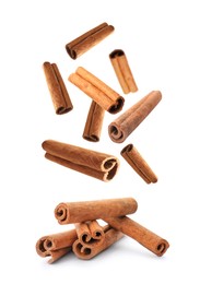 Image of Aromatic cinnamon sticks falling on white background