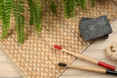 Flat lay composition with natural bamboo toothbrushes on wooden table