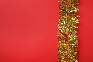 Golden tinsel on red background, top view. Space for text