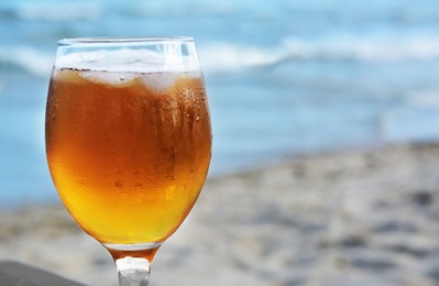 Cold beer in glass on beach, closeup. Space for text