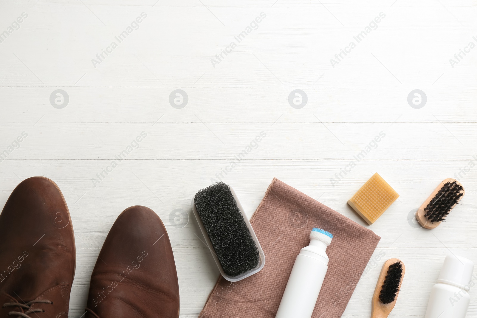 Photo of Stylish footwear with shoe care accessories on white wooden table, flat lay. Space for text