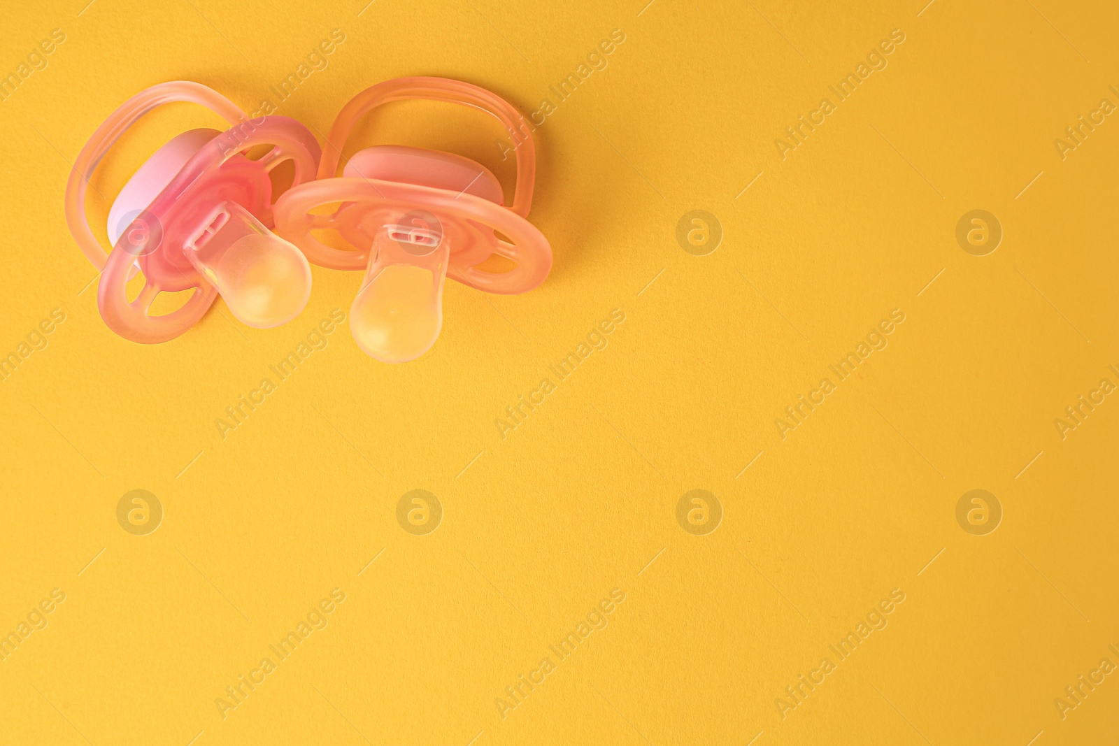 Photo of New baby pacifiers on orange background, flat lay. Space for text