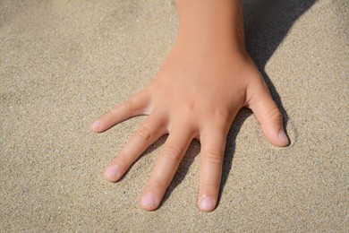 Photo of Child leaving handprint on sand outdoors, closeup. Fleeting time concept