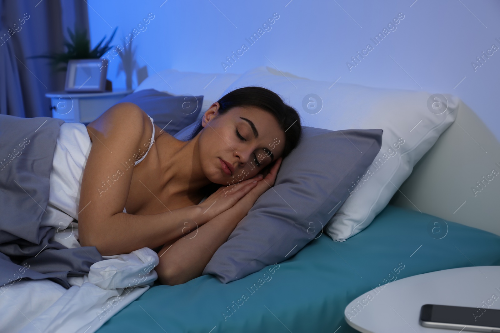 Photo of Young woman sleeping on soft pillow at night. Bedtime