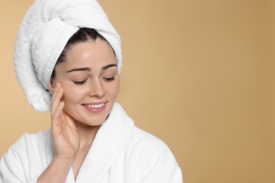 Photo of Portrait of attractive young woman in bathrobe with towel on beige background, space for text. Spa treatment