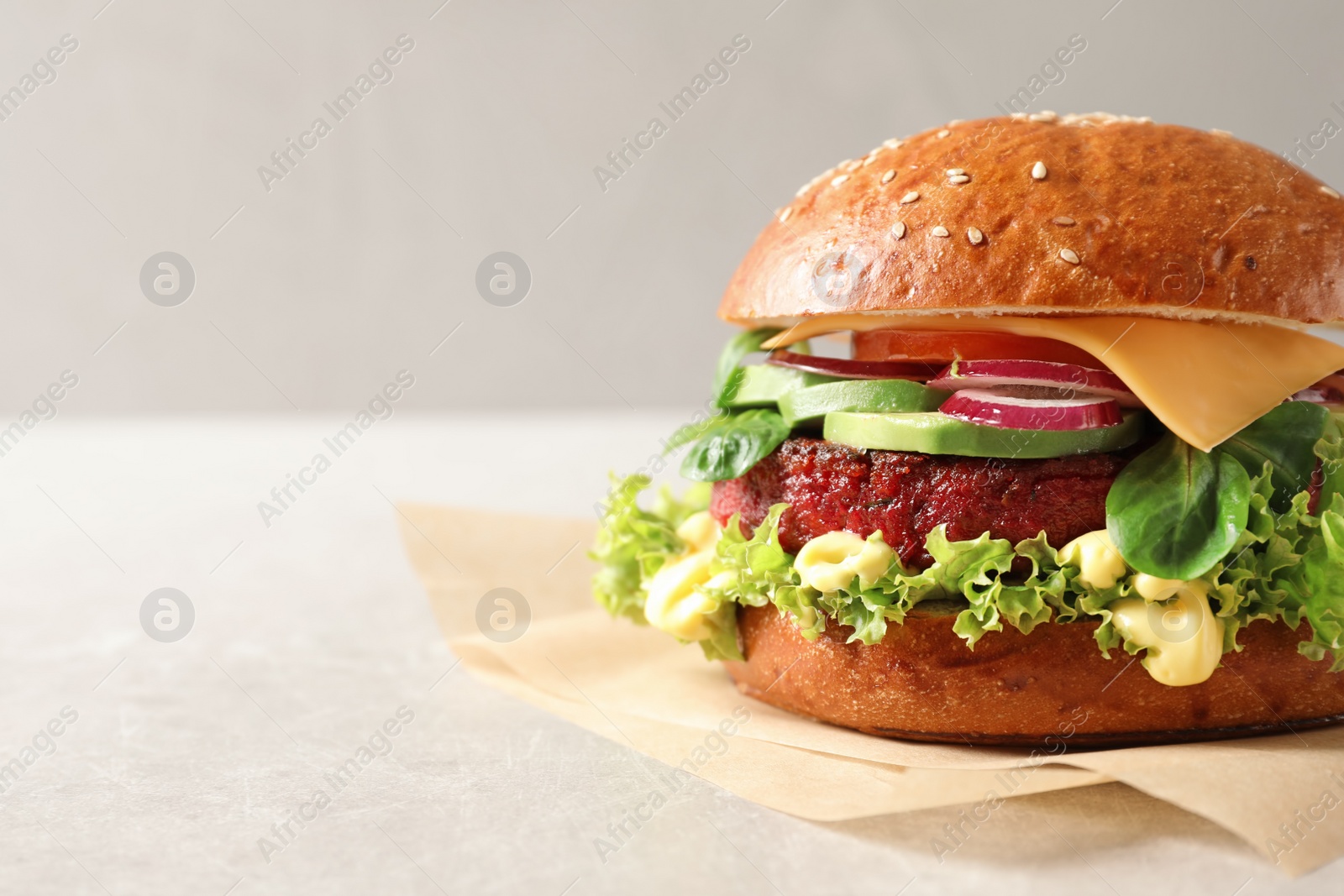 Photo of Tasty vegetarian burger with beet cutlet on table against light background. Space for text