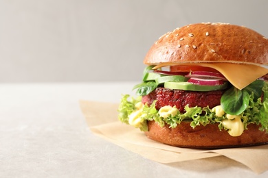 Tasty vegetarian burger with beet cutlet on table against light background. Space for text