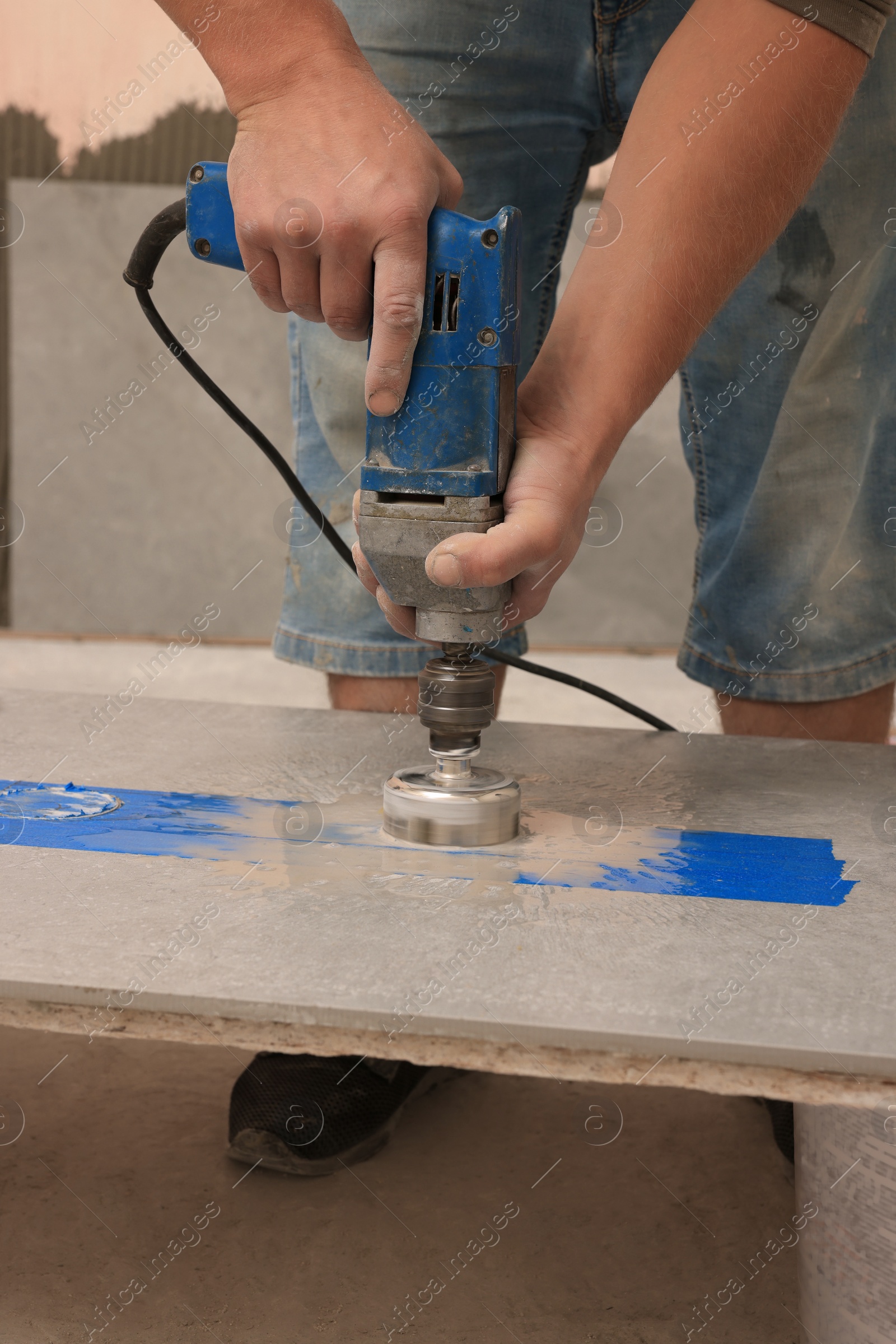 Photo of Worker making socket hole in tile indoors, closeup