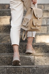 Photo of Young woman with stylish beige backpack on stairs outdoors, closeup