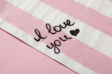 Napkin with handwritten message I Love You on pink table