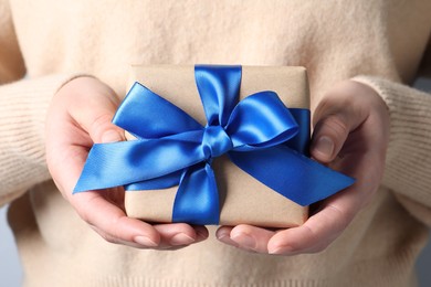Photo of Woman holding gift box with blue bow, closeup