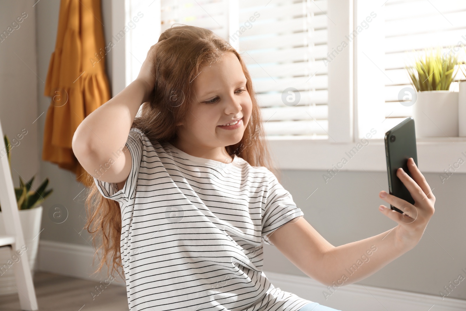 Photo of Cute little girl taking selfie at home