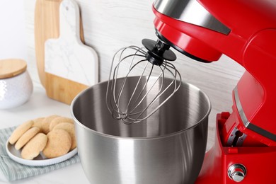 Photo of Modern red stand mixer and cookies on white table, closeup