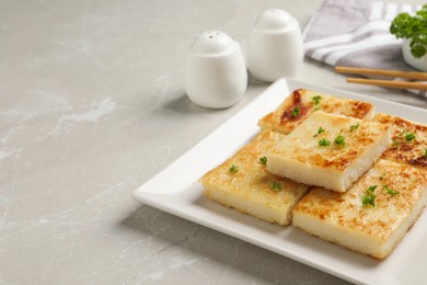 Photo of Delicious turnip cake with parsley served on light table. Space for text