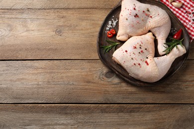 Photo of Raw chicken leg quarters and ingredients on wooden table, flat lay. Space for text