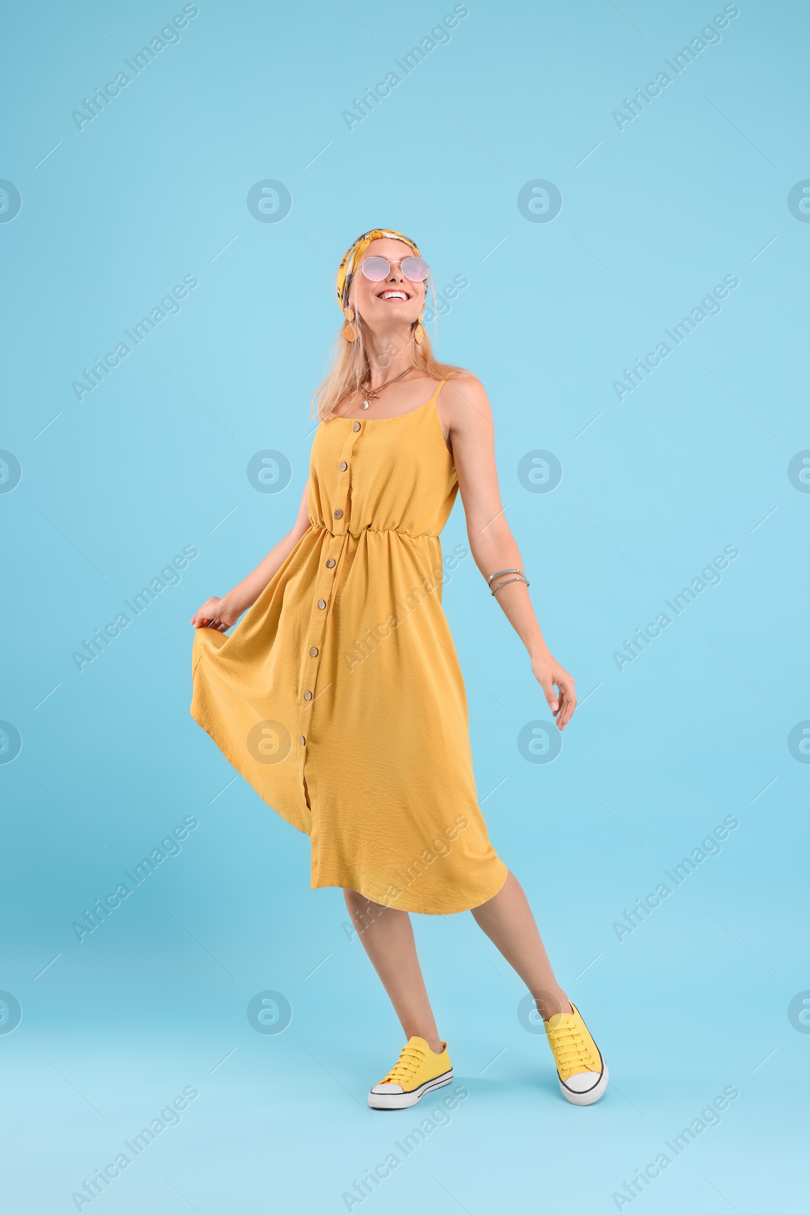 Photo of Portrait of smiling hippie woman dancing on light blue background