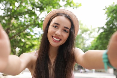 Beautiful young woman taking selfie outdoors on sunny day