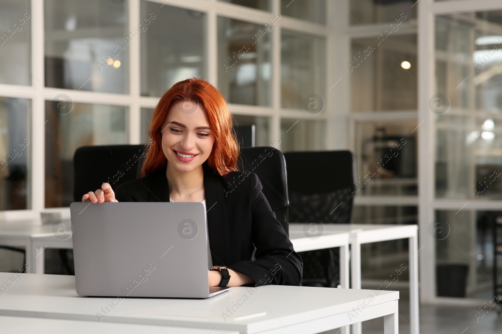 Photo of Happy woman working with laptop at white desk in office