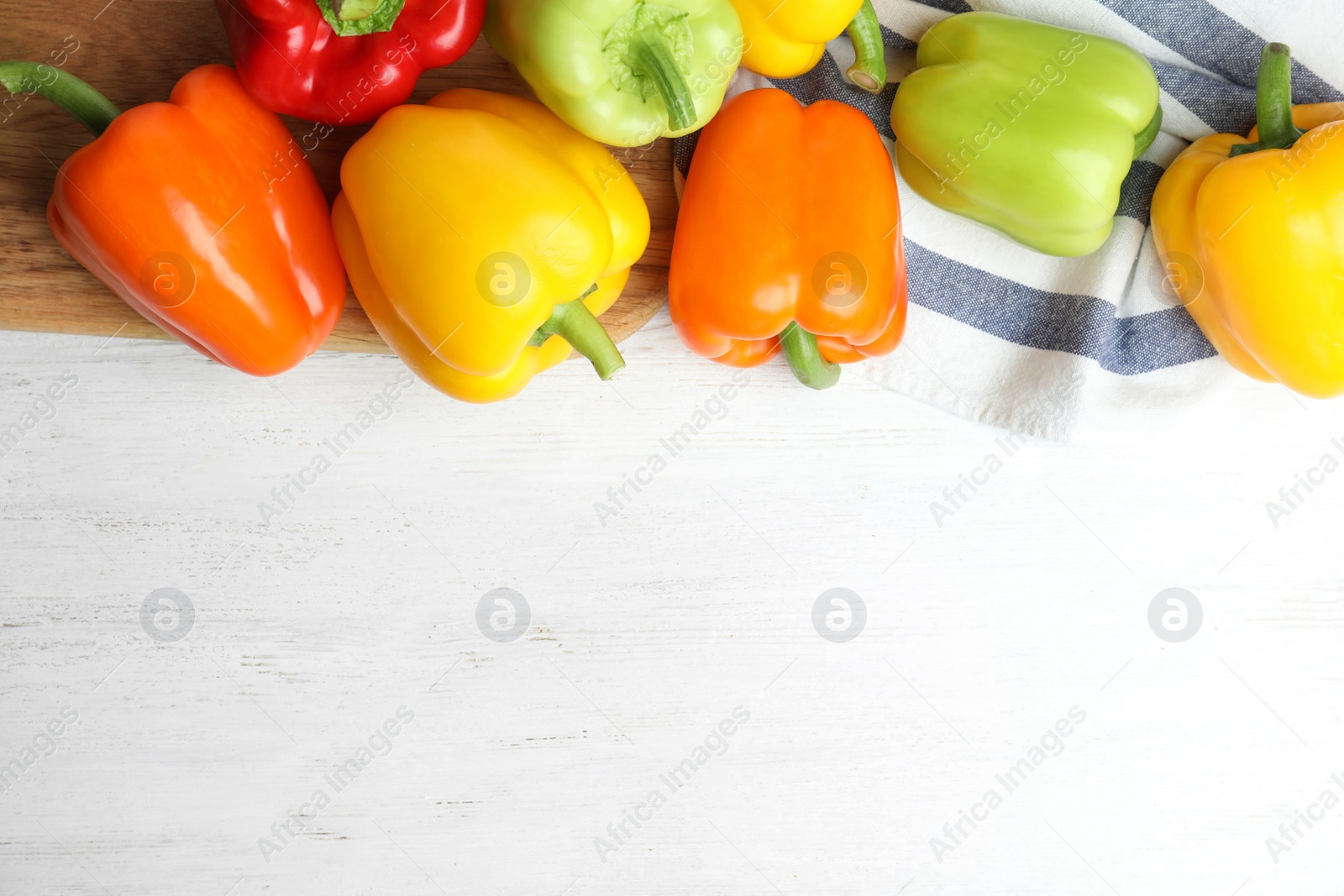 Photo of Flat lay composition with fresh ripe bell peppers on white wooden table, space for text