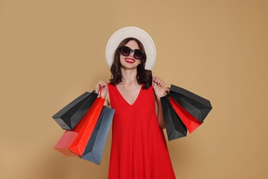 Photo of Beautiful young woman with paper shopping bags on beige background