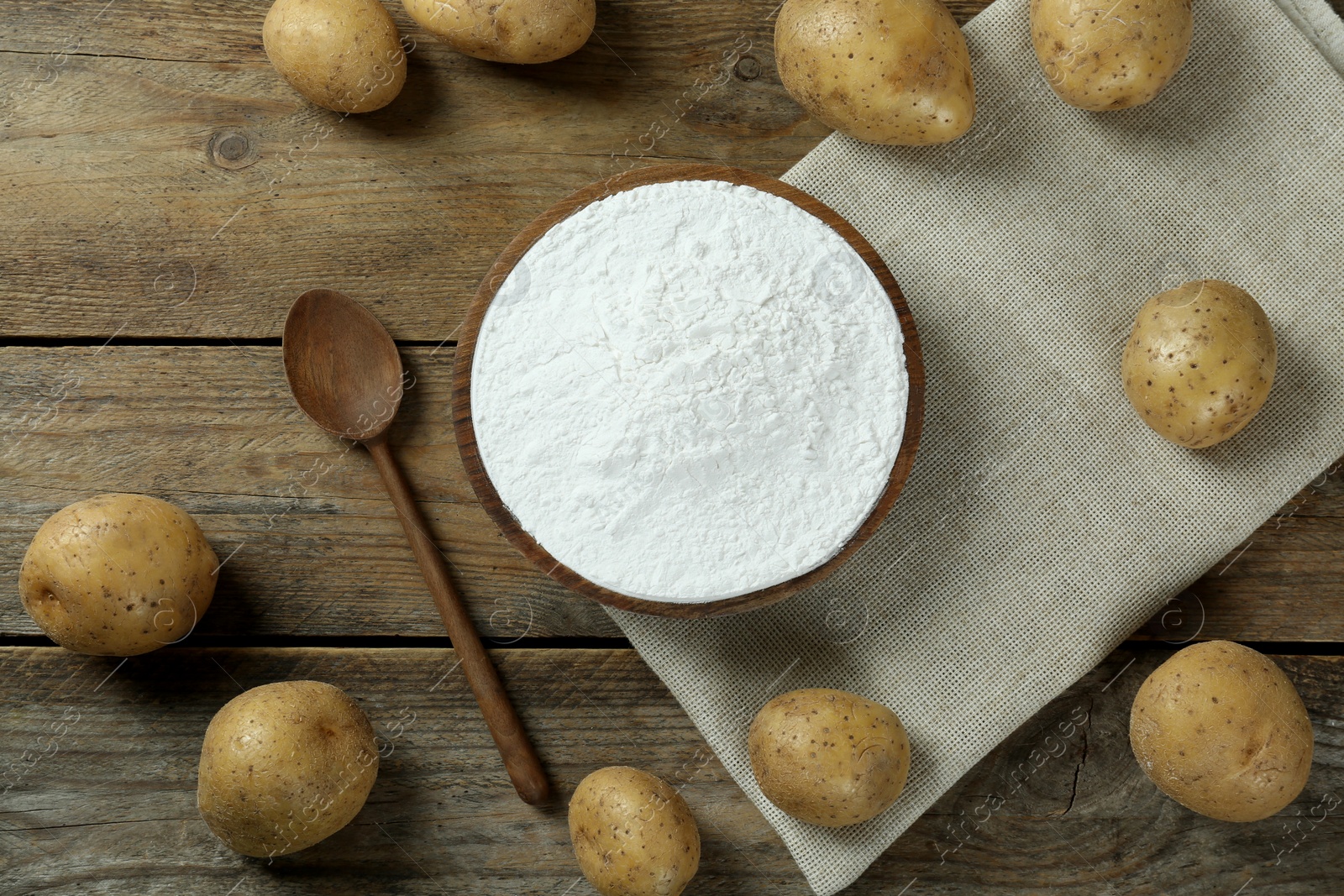 Photo of Starch and fresh raw potatoes on wooden table, flat lay