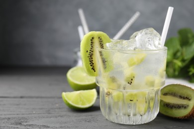 Photo of Glass of refreshing drink and cut kiwi on gray table, closeup. Space for text