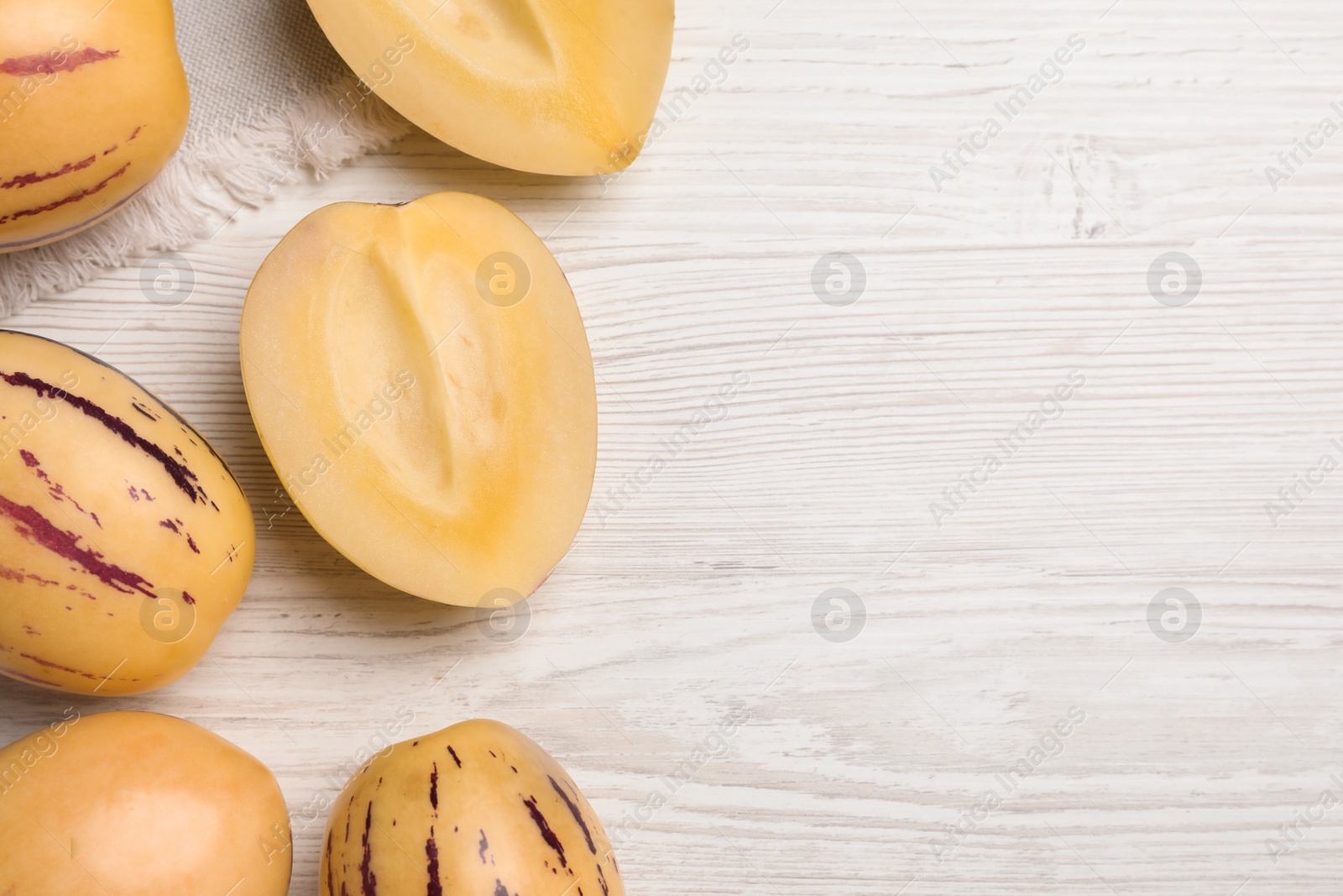 Photo of Fresh ripe pepino melons on white wooden table, flat lay. Space for text