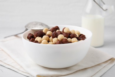 Photo of Breakfast cereal. Tasty corn balls with milk in bowl and spoon on table, closeup