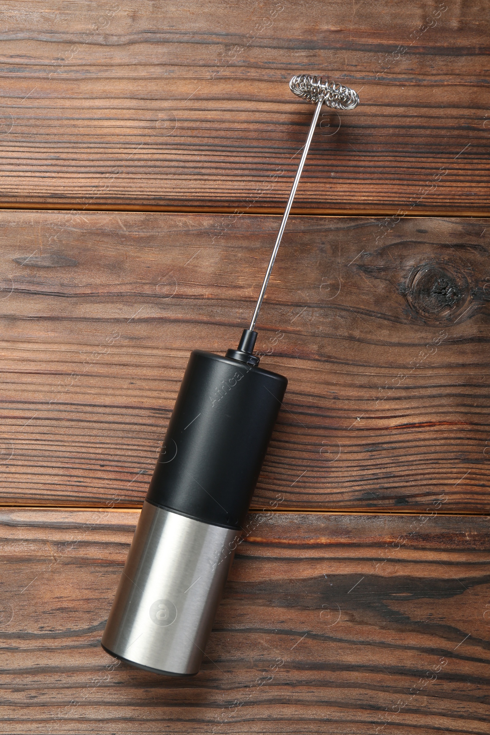 Photo of Black milk frother wand on wooden table, top view