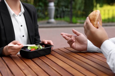 Photo of Colleagues having business lunch at wooden table outdoors, closeup