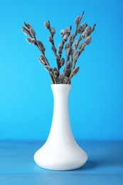 Photo of Beautiful bouquet of pussy willow branches on light blue wooden table