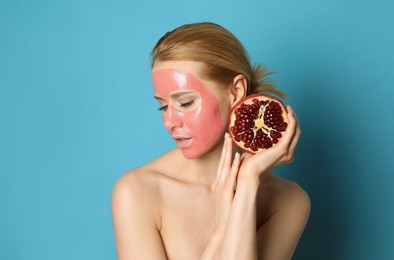 Young woman with pomegranate face mask and fresh fruit on light blue background