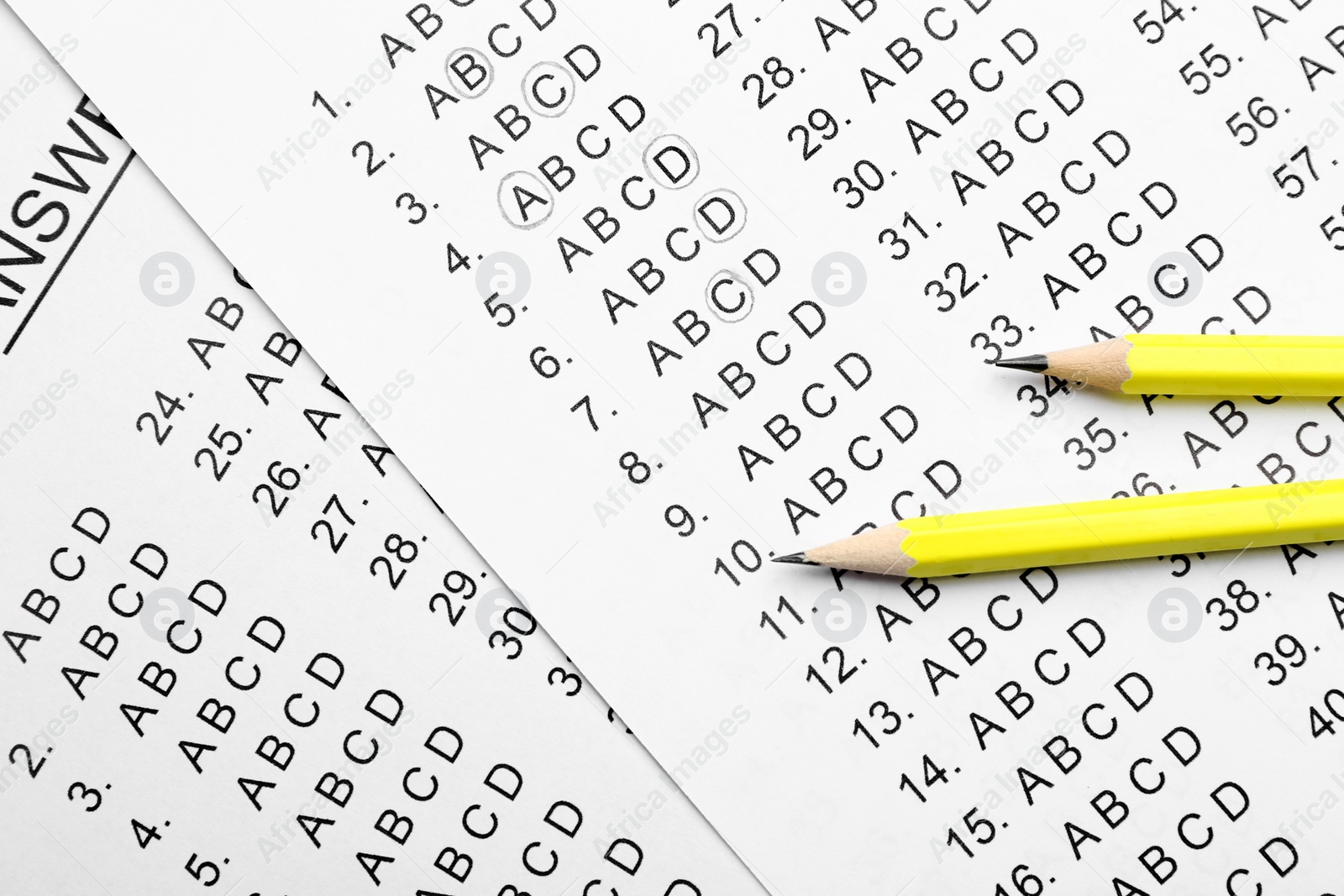 Photo of Yellow pencils on answer sheets, top view