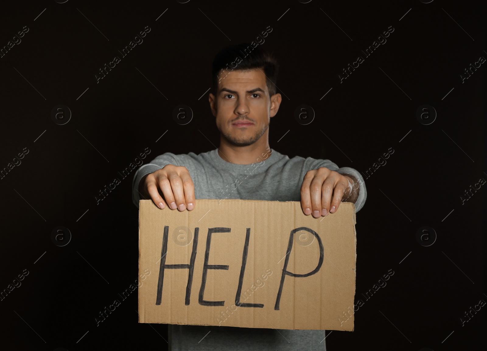 Photo of Unhappy man with HELP sign on dark background