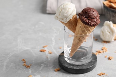 Photo of Tasty ice cream scoops in waffle cones on grey marble table, closeup. Space for text