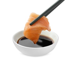 Dipping tasty salmon sashimi into soy sauce isolated on white